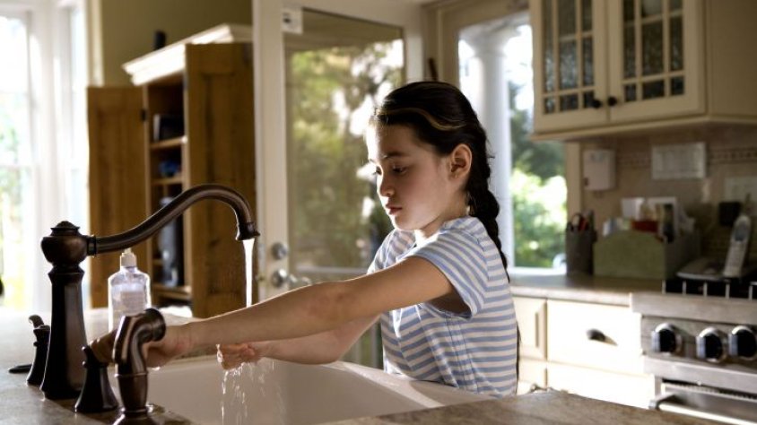 Una nena agafant aigua de l'aixeta