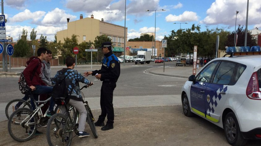 Un agent de la Policia Local dóna consells de seguretat viària a uns joves que van amb bicicleta