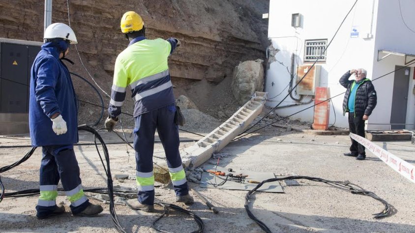 Dos operaris, davant de la torre elèctrica abatuda per una roca a l'estació de servei de la Portella