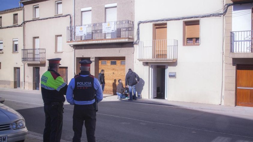 ossos custodiant la casa on es va produir el succés, en primer pla, i agents d'investigació i de la científica, al fons