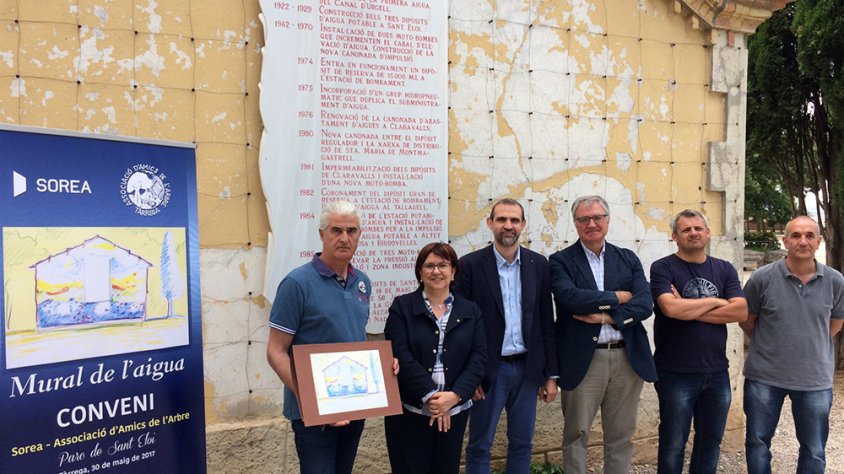 L’alcaldessa Rosa Maria Perelló; el president dels Amics de l’Arbre, Jaume Aligué; el gerent territorial de Sorea, David Gall; l’autor del futur mural, Josep Castellana; i membres dels Amics de l’Arbre, davant la façana que s’ornamentarà