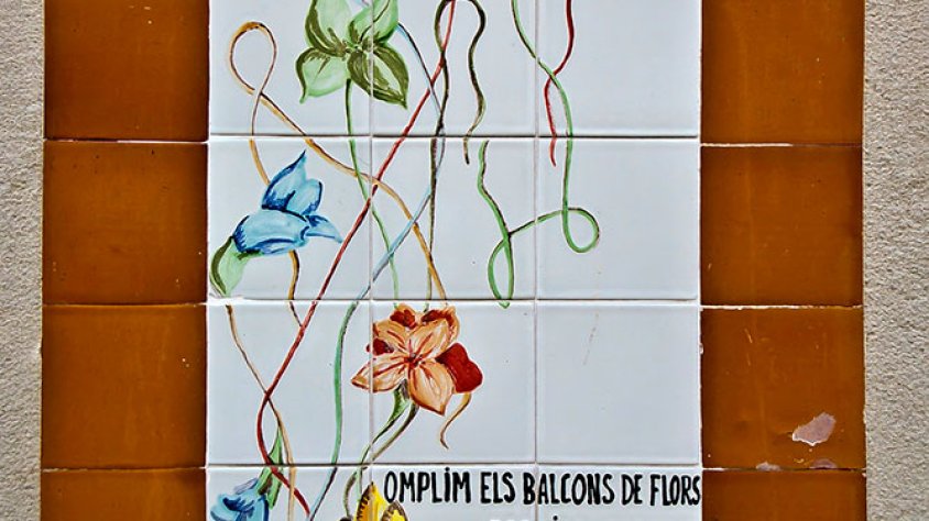 La ceràmica que recorda el Premi al Carrer 1983 en el concurs 'Omplim els Balcons de Flors', al carrer de les Piques