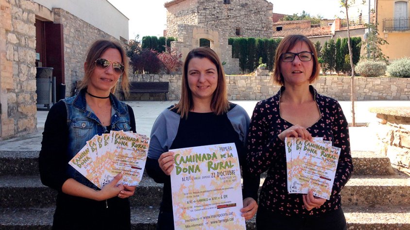 La regidora de Turisme, Desenvolupament Rural i Pobles, Mireia Caus; la tècnica de Polítiques d’Igualtat, Mireia Fontanet; i la portaveu de la Junta de Veïns d’Altet, Núria Valls; amb els cartells de l’activitat davant el Local Social d’Altet