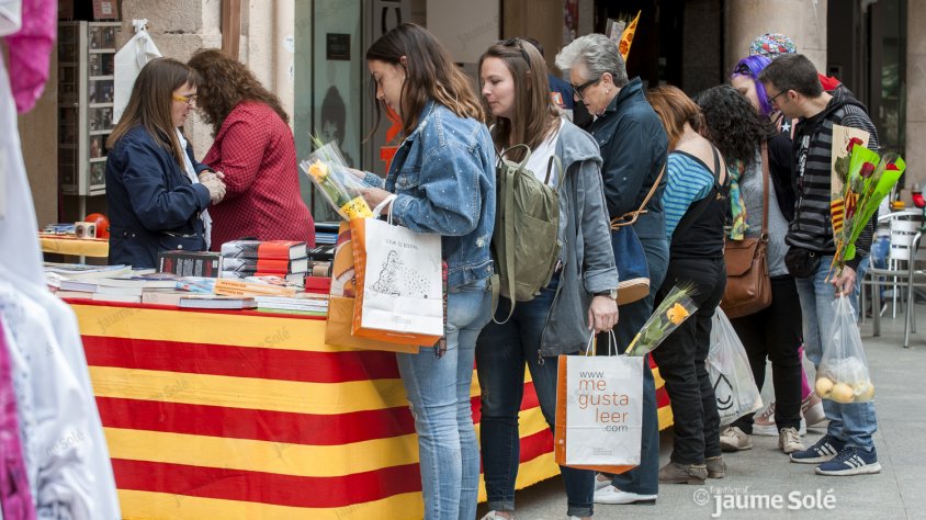 Públic a la parada de la llibreria Sauret, on es veu gent amb roses vermelles i grogues