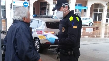 Un agent lliurant una mascareta a un senyor gran que avui anava pel carrer
