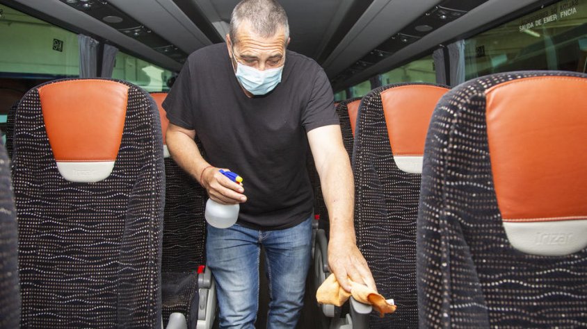 Un treballador netejant els seients d'un autocar