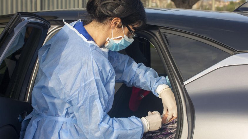 Una sanitària vacunant una persona sense sortir del cotxe