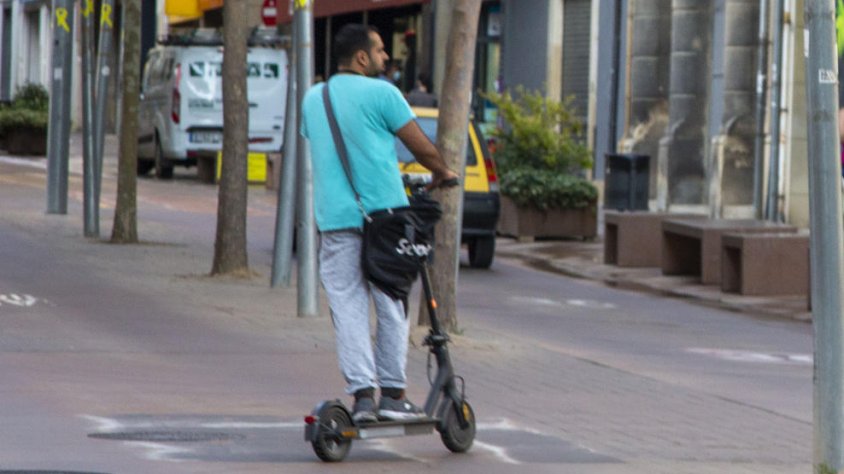 Foto d'arxiu d'un conductor de patinet elèctric travessant l'avinguda Catalunya