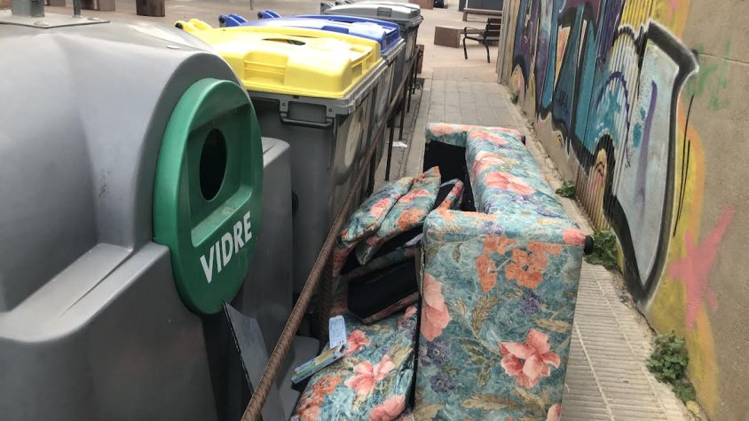 Un sofà al costat d'un contenidor d'un cèntric carrer de Tàrrega