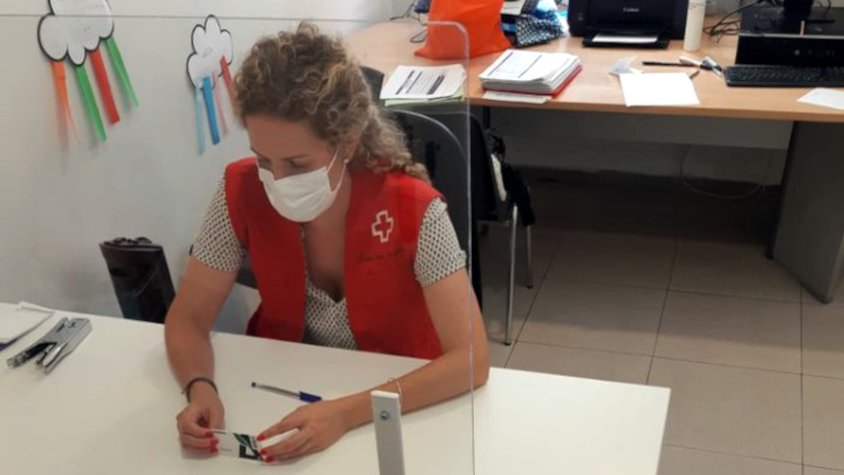 Una voluntària de Creu Roja repartint targetes moneder.