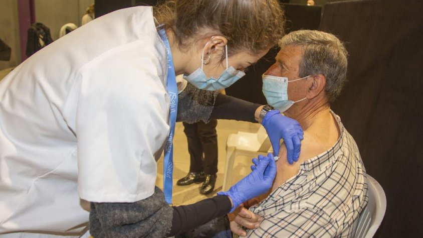 Una professional sanitària administrant la dosi de record a una persona major de 65 anys