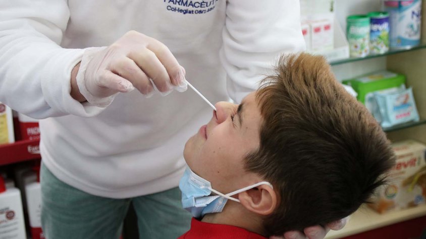 Primer pla d'un nen mentre un farmacèutic li fa un test