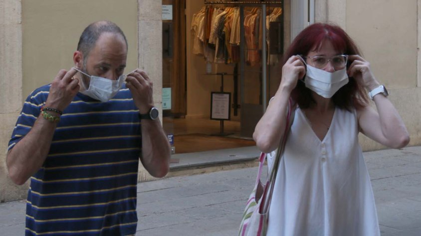 Dues persones col·locant-se la mascareta abans d'entrar a un comerç