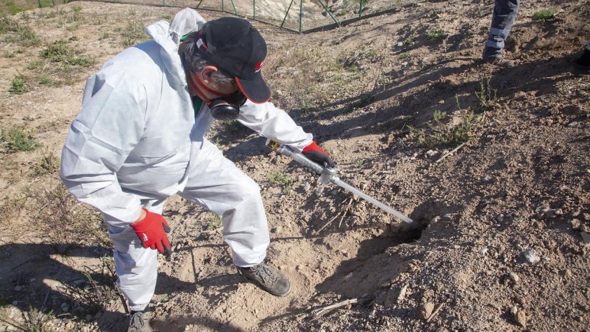 Un tècnic aplica el biocida en un forat al costat de la bassa