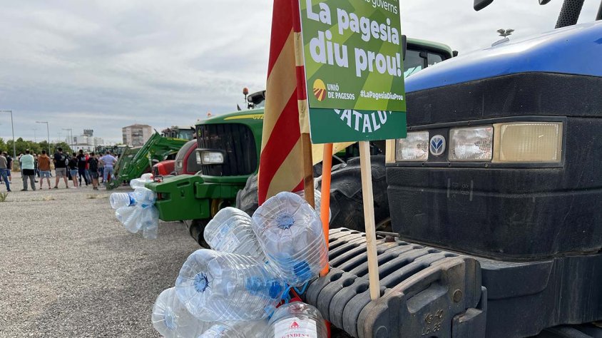 Garrafes buides d'aigua penjades del morro d'un tractor
