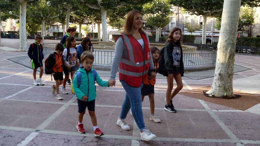 Un grup d'infants camina amb una monitora en un dels camins escolars habilitats