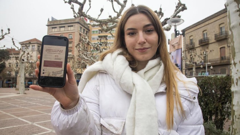 Txell Capdevila mostrant el cartell de l'acció de dissabte a través del mòbil al Pati