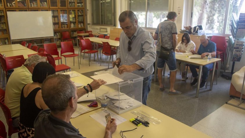 Un veí votant en una de les meses del col·legi electoral habilitat a l'institut Manuel de Pedrolo