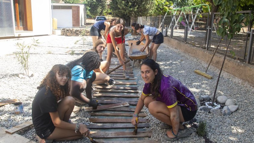 Algunes de les joves ultimant la pintura a les peces de fusta que conformen el nou camí