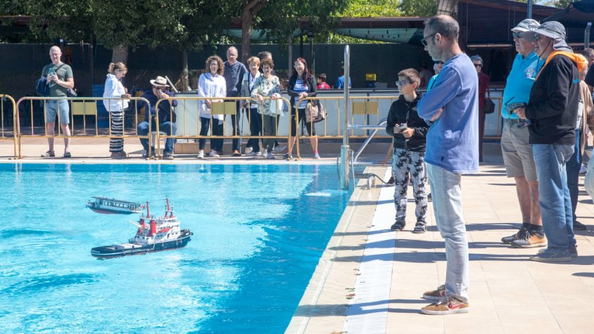 Aficionats participants fent navegar les seues embarcacions i públic contemplant les maquetes