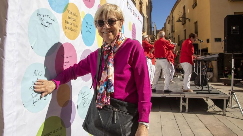 Una dona enganxant una frase al mural participatiu