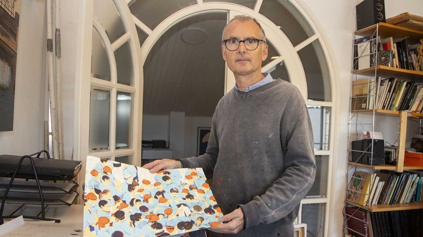Magí Puig mostrant la litografia dedicada als Castellers que forma part del volum