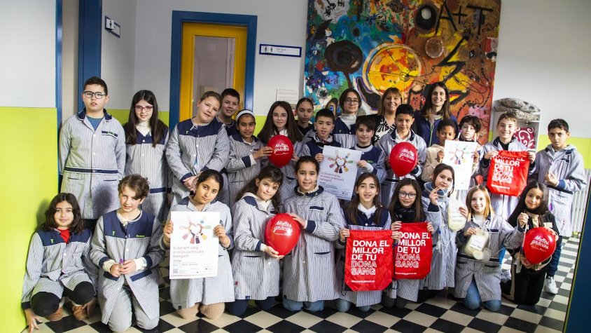 ls alumnes de 5è de Primària mostrant el cartell de la campanya i obsequis per als donants