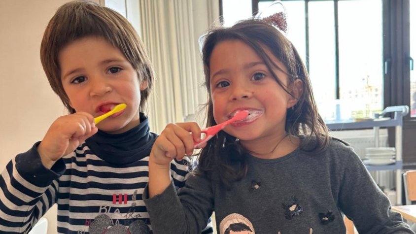 Dos infants rentant-se les dents al menjador de l'escola